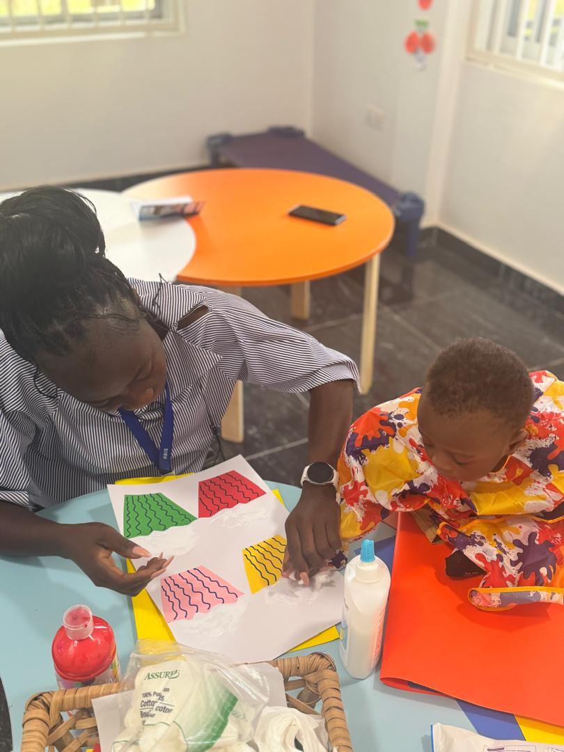 Teacher guiding a child during a creative class activity